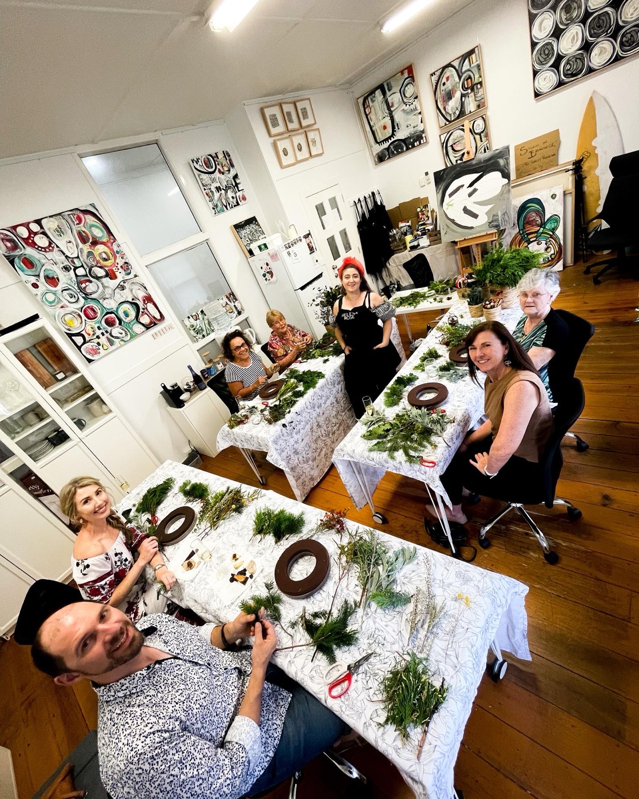 A wreath-making workshop in progress at Studio on Brunswick — participants assembling foliage around the long workshop table